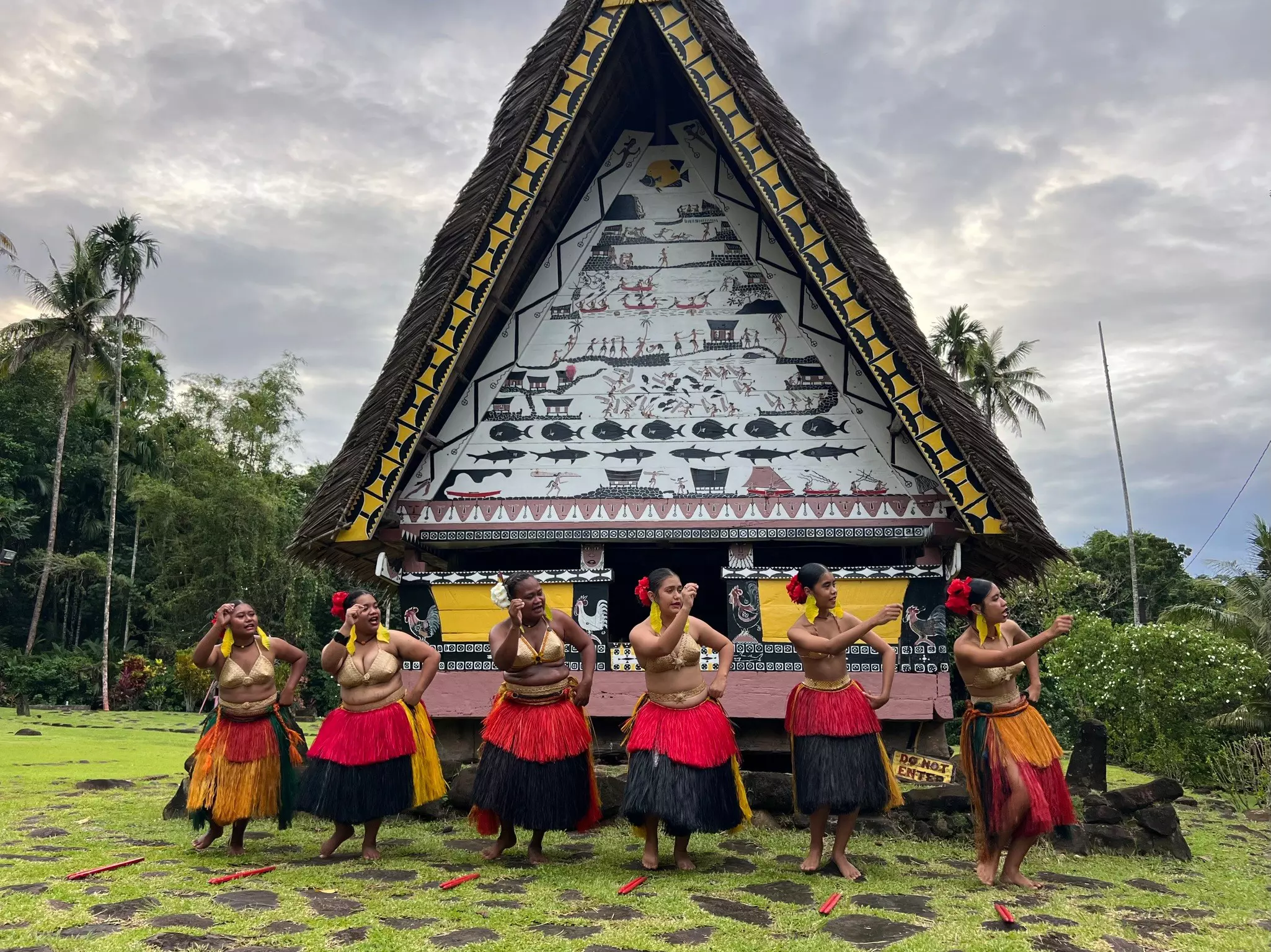 Women in grass skirts perform a traditional dance in front of the bai in Airai, Palau.