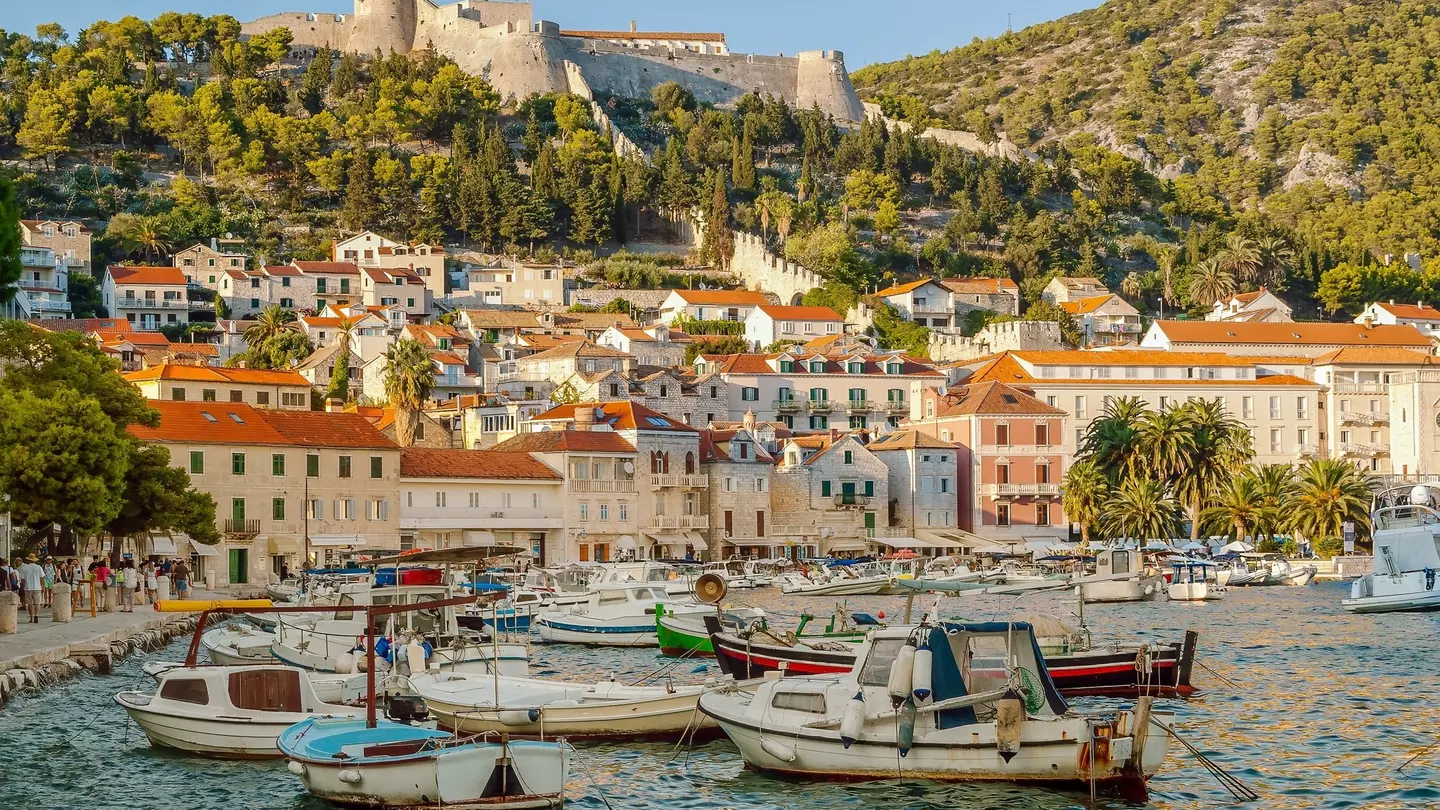 Boats are docked in a harbor that is surrounded by beautiful stone buildings and a variety of restaurants and cafes.