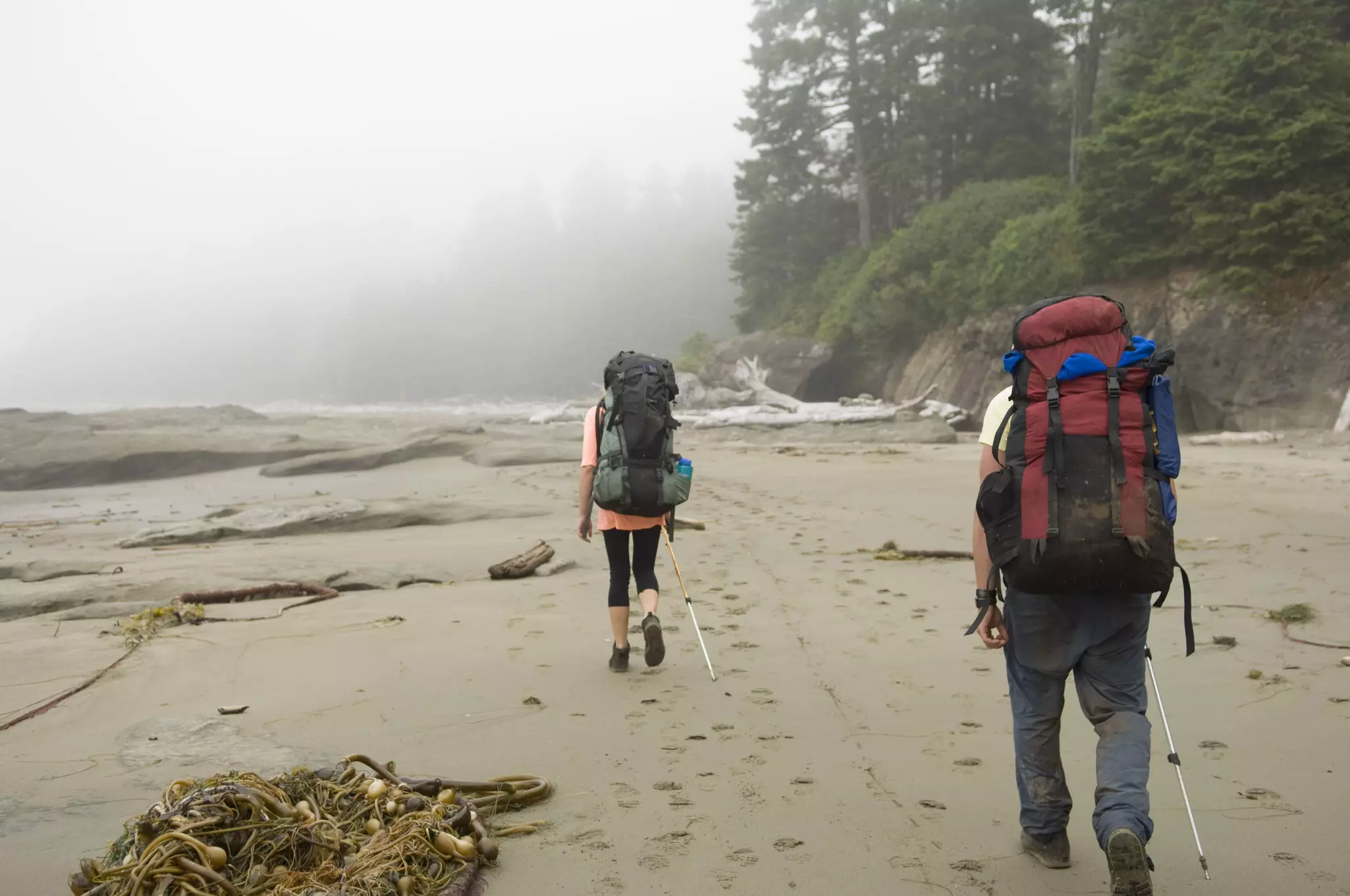 A pair of hikers backpacking across a beach on the West Coast Trail, Vancouver Island