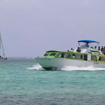A ferry boat glides through the water past a small sailboat.