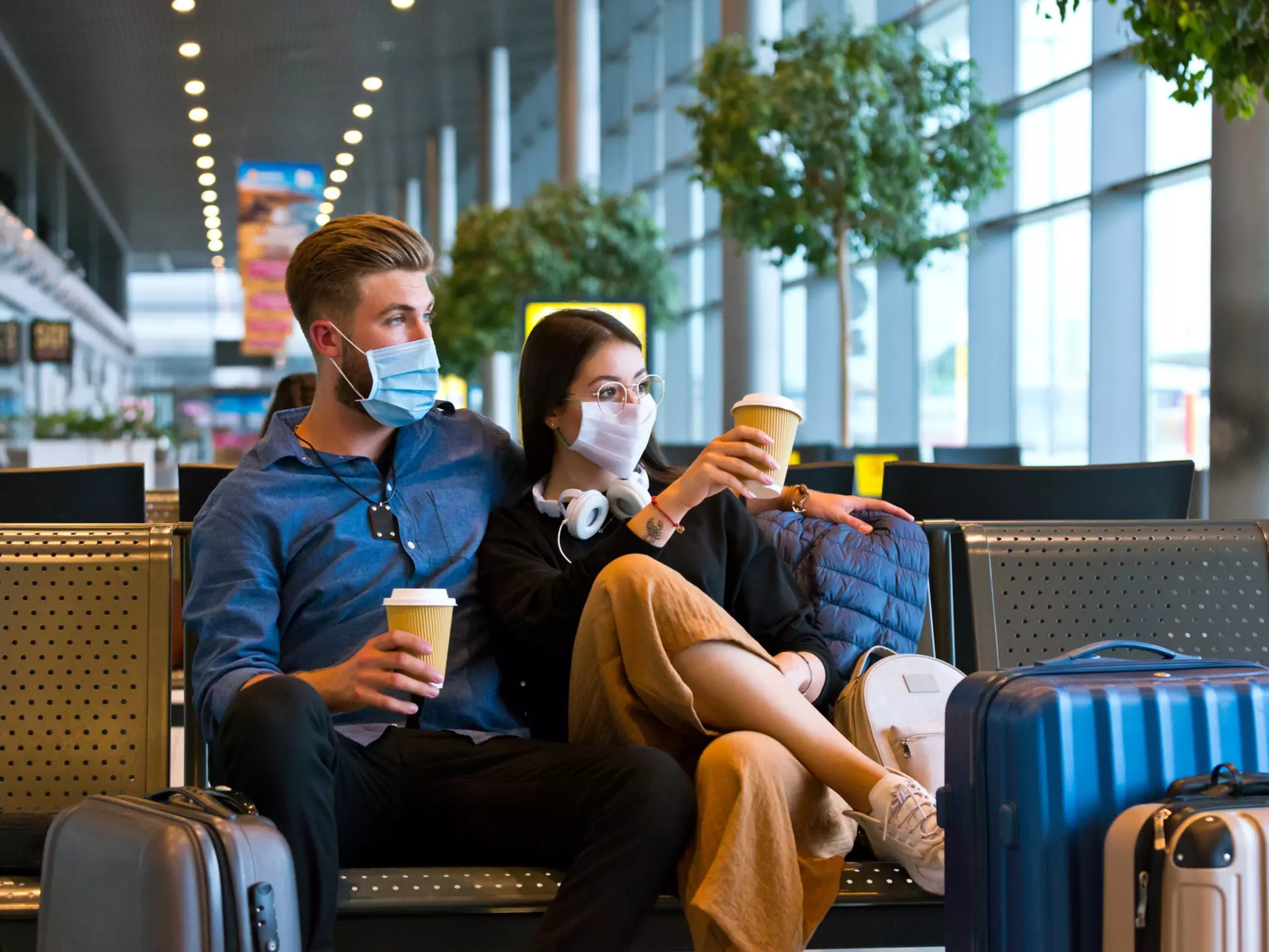Young couple wearing N95 face masks waiting in airport area