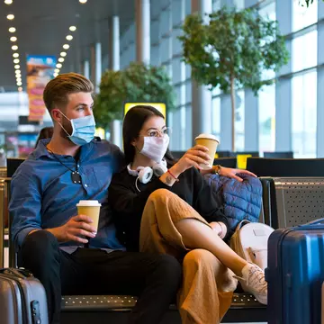 Young couple wearing N95 face masks waiting in airport area