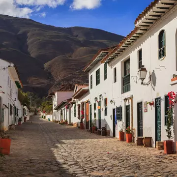 Villa de Leyva, Colombia - September 14, 2014:  It is Sunday morning in Villa de Leyva and Calle or Street 14 is almost lifeless.  The shops and restaurants will open; but, only towards noon.  Founded in 1572 and located at just over 7000 feet above sea level on the Andes Mountains, Villa de Leyva was declared a National Monument in 1954 to protect it's colonial architecture and heritage. It is located in the Department of Boyaca, in the South American country of Colombia.  In the background are the always present Andes Mountains.  Photo shot in the morning sunlight; horizontal format. Copy space.