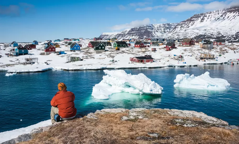 Rear view of a man sat admiring wonderful views of Qeqertarsuaq, a small town in Greenland