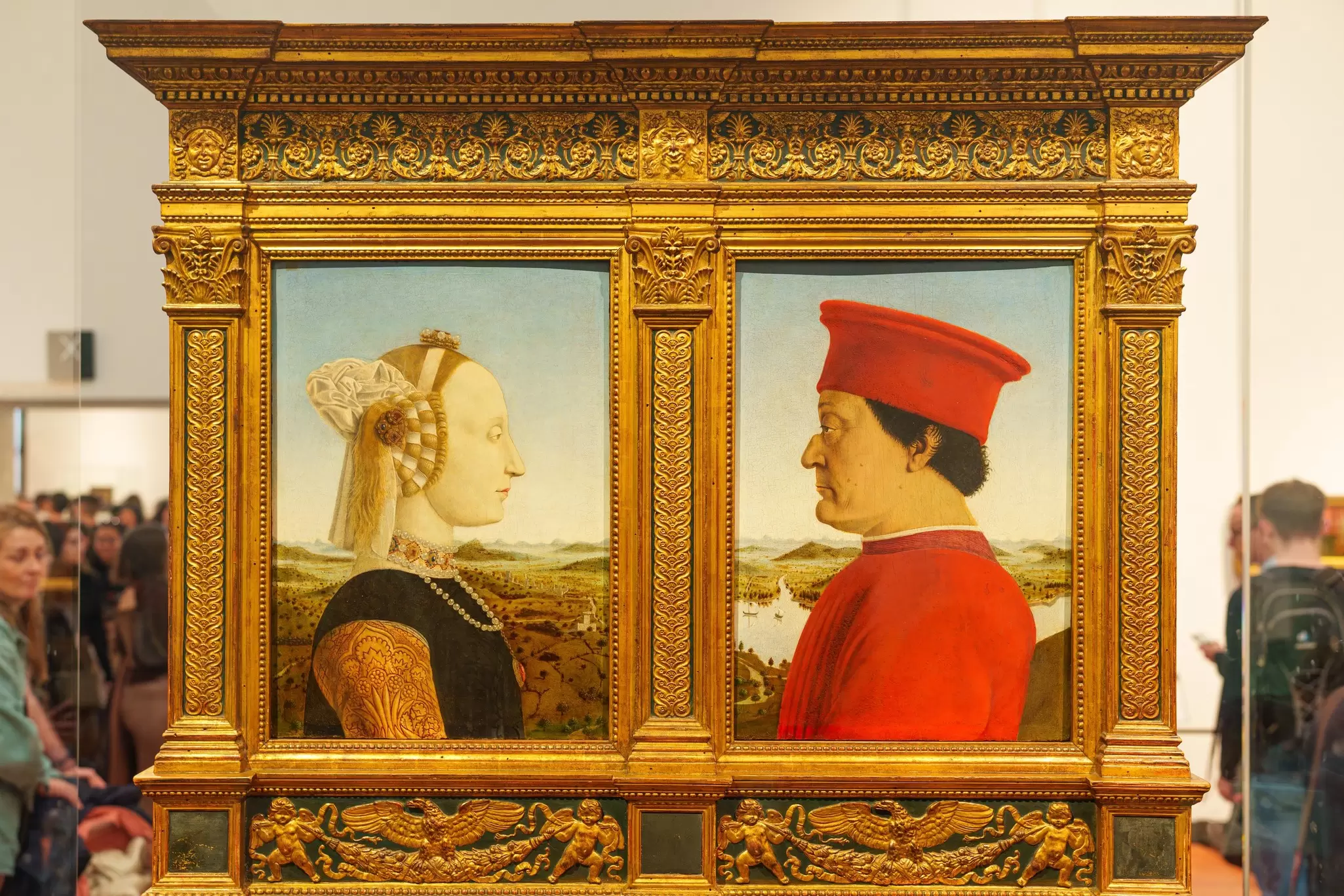 Two people are depicted in a diptych portrait displayed in a museum gallery
