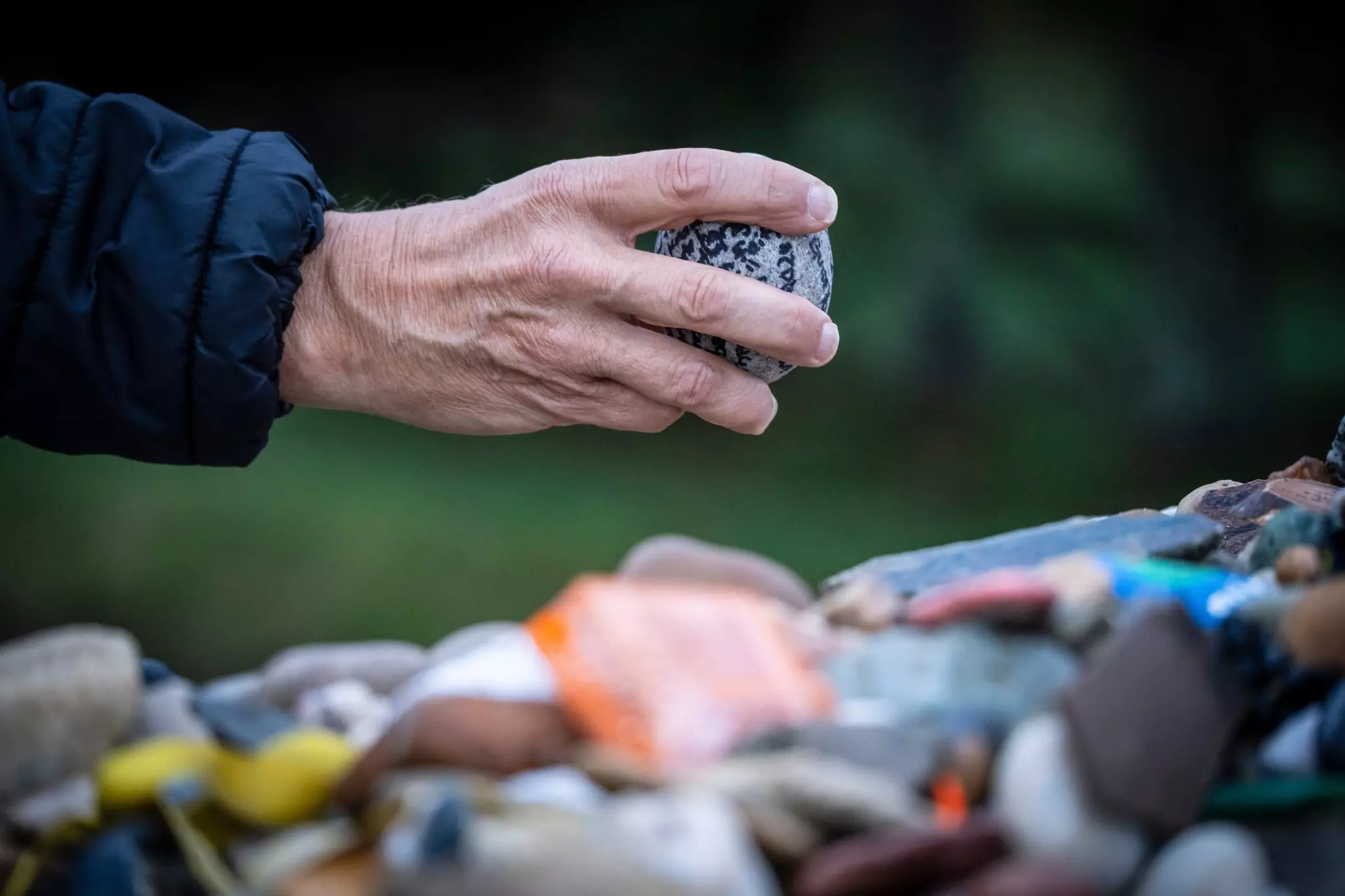 Pilgrim on the Camino de Santiago offering votive stones and offerings  in Cruz de Ferro (Iron Cross), Foncebadón hill, Bierzo region,, Castile and Leon, Spain