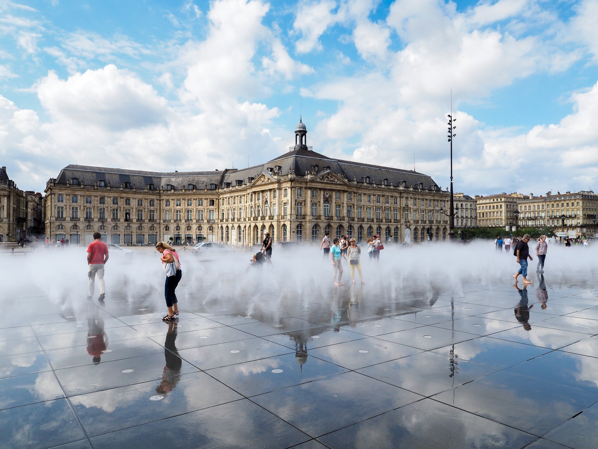 People walking through the Miroir d'Eau at Place de la Bourse in Bordeauxm France. 