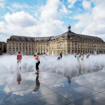 People walking through the Miroir d'Eau at Place de la Bourse in Bordeauxm France. 