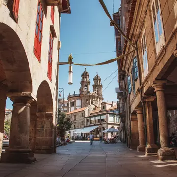 View down a street in the old town of Pontevedra, Spain, with the towers of the Santuario da Virxe Peregrina in the background.