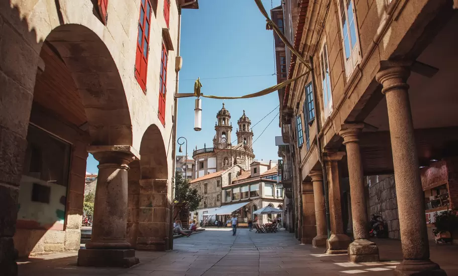 View down a street in the old town of Pontevedra, Spain, with the towers of the Santuario da Virxe Peregrina in the background.