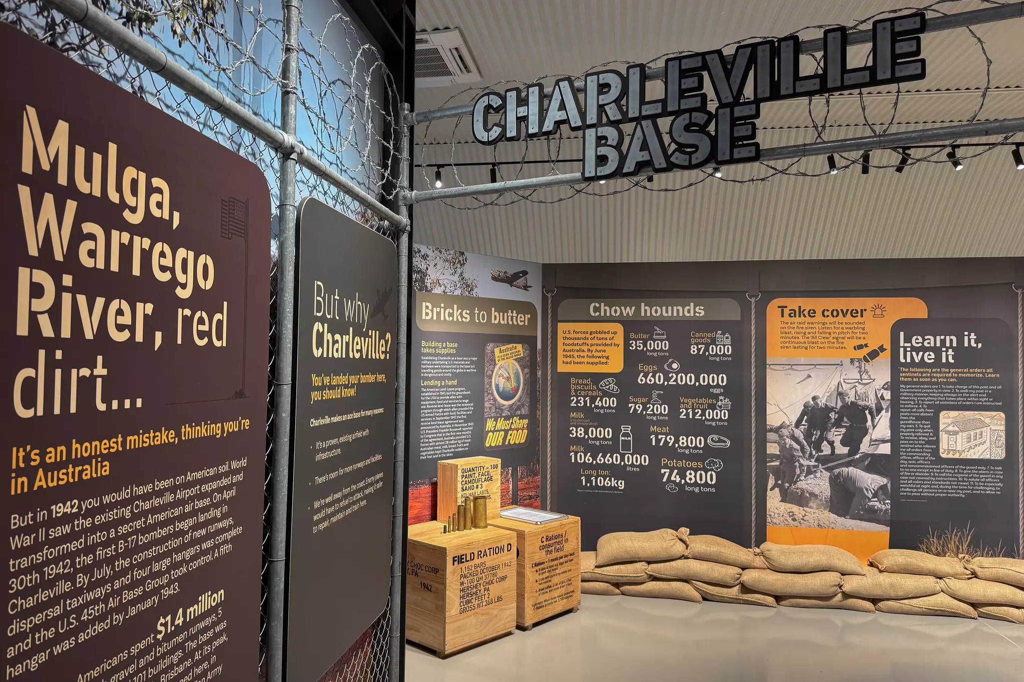 A museum display on World War II, with text, images and data, as well as sandbags and barb wire.