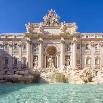 The blue waters of Trevi Fountain are backed by the grandiose Baroque sculptures and mansion-like facade