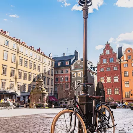 A bicycle leaning against a lamppost a cobblestone square.