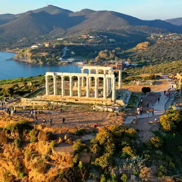 Aerial drone photo of archaeological site of Cape Sounio with iconic ruins of Temple of Poseidon at sunset, Attica, Greece