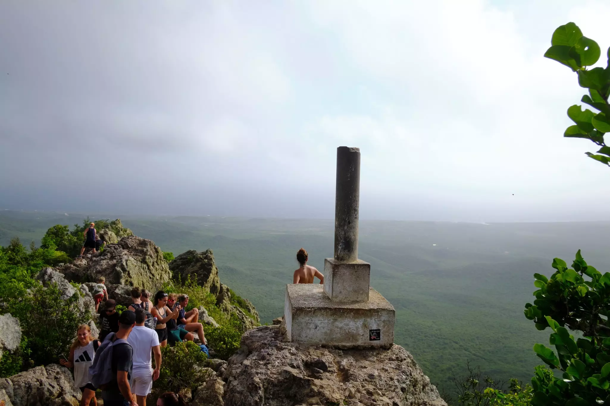 Hikers at a viewpoint at the top of a mountain with views that stretch over rolling green hills and down to the sea.