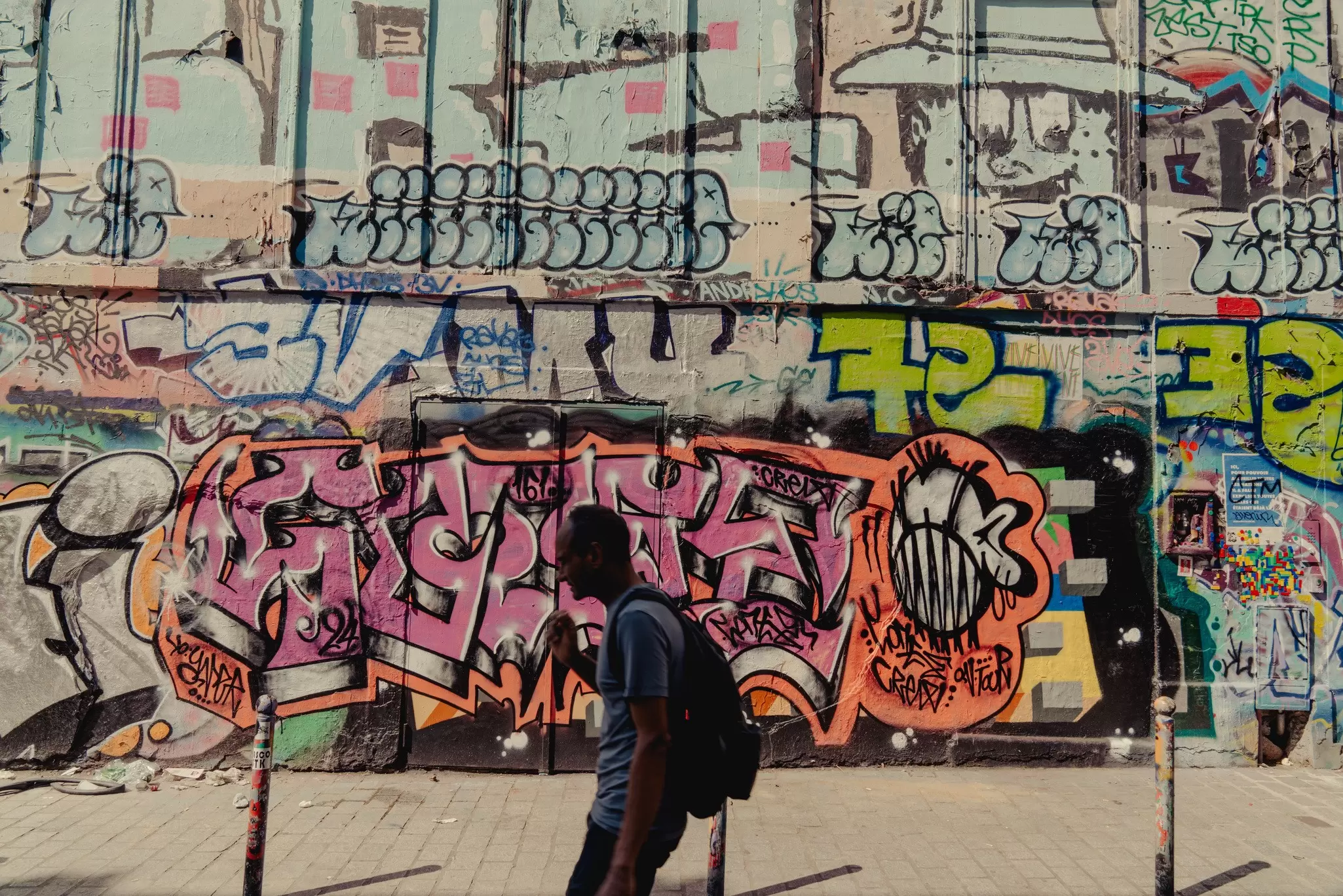 A man walking past a wall of graffiti