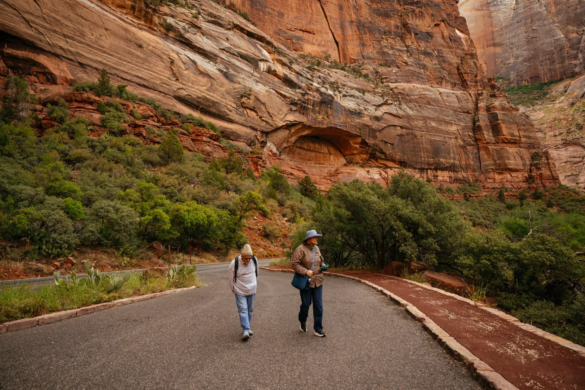 Two people on a road with ruddy mountains in the background