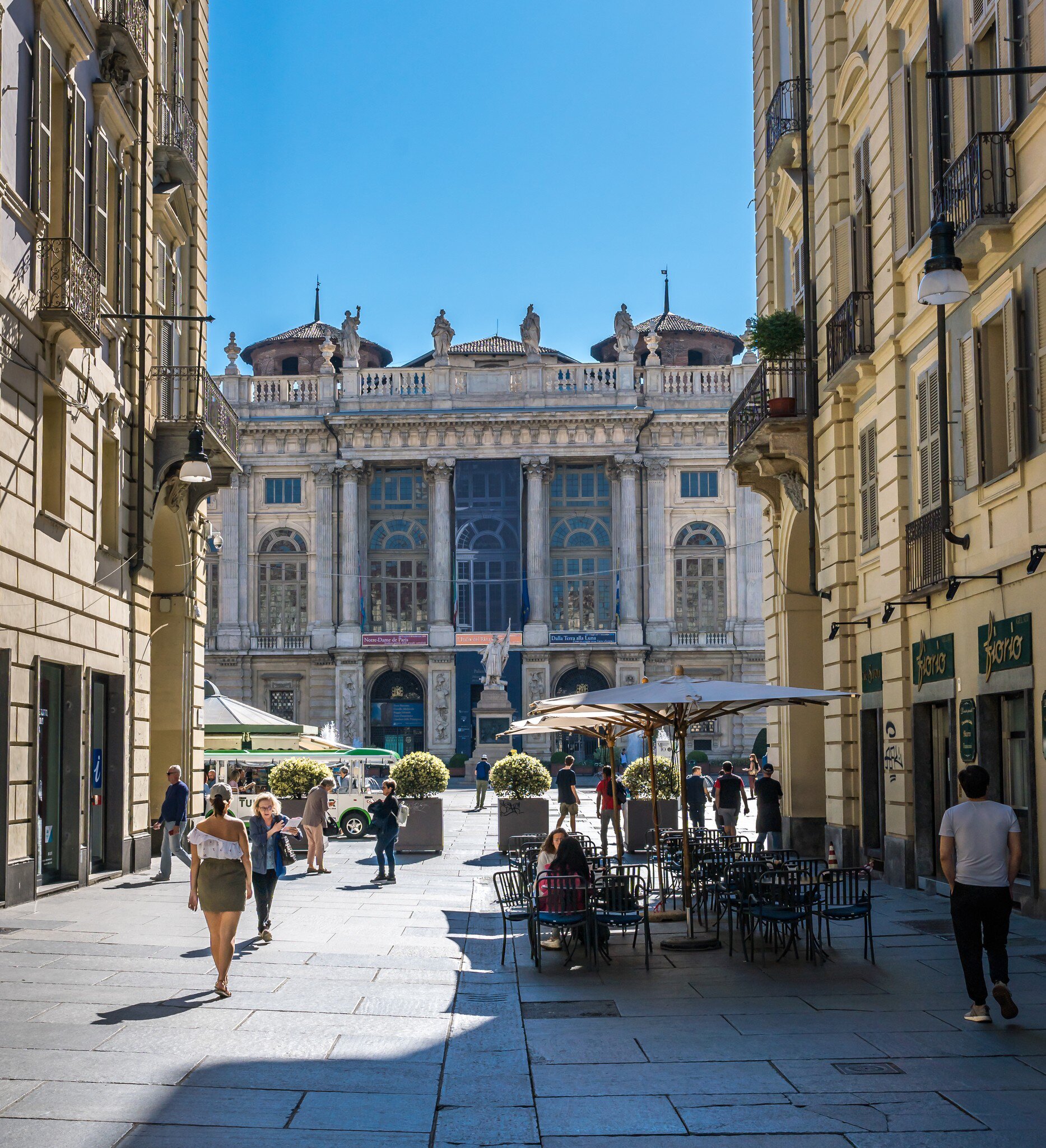 People walking around Via Garibaldi of Madama Palace (Palazzo) in Piazza Castello on a sunny day.