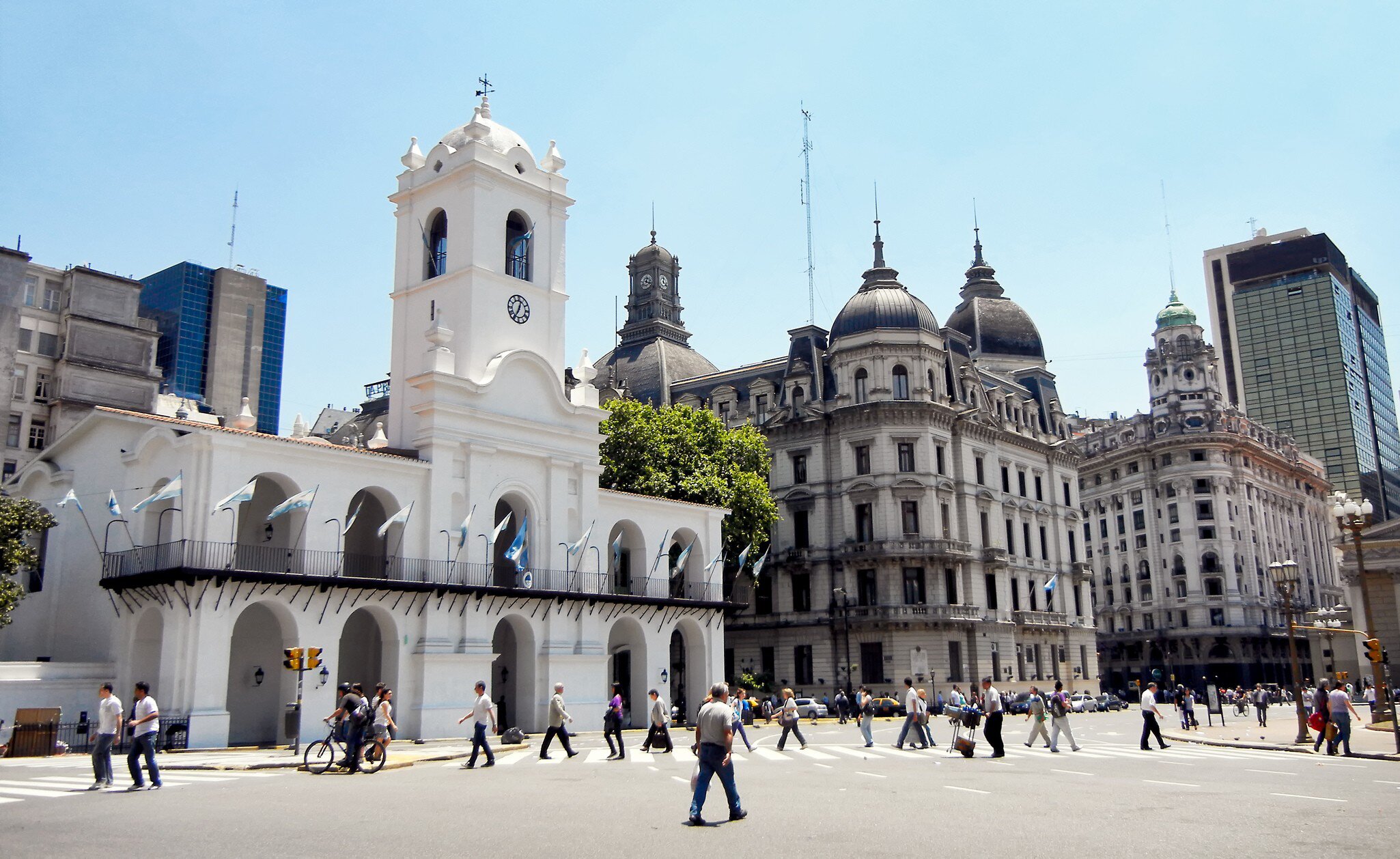 Exterior of the historic Cabildo Nacional building in Plaza de Mayo, Buenos Aires. Pedestrians walking on busy street in foreground.