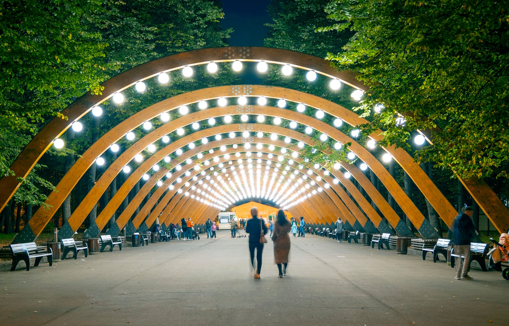 The main wooden arch with light and walking people in Sokolniki park, Moscow,  Russia