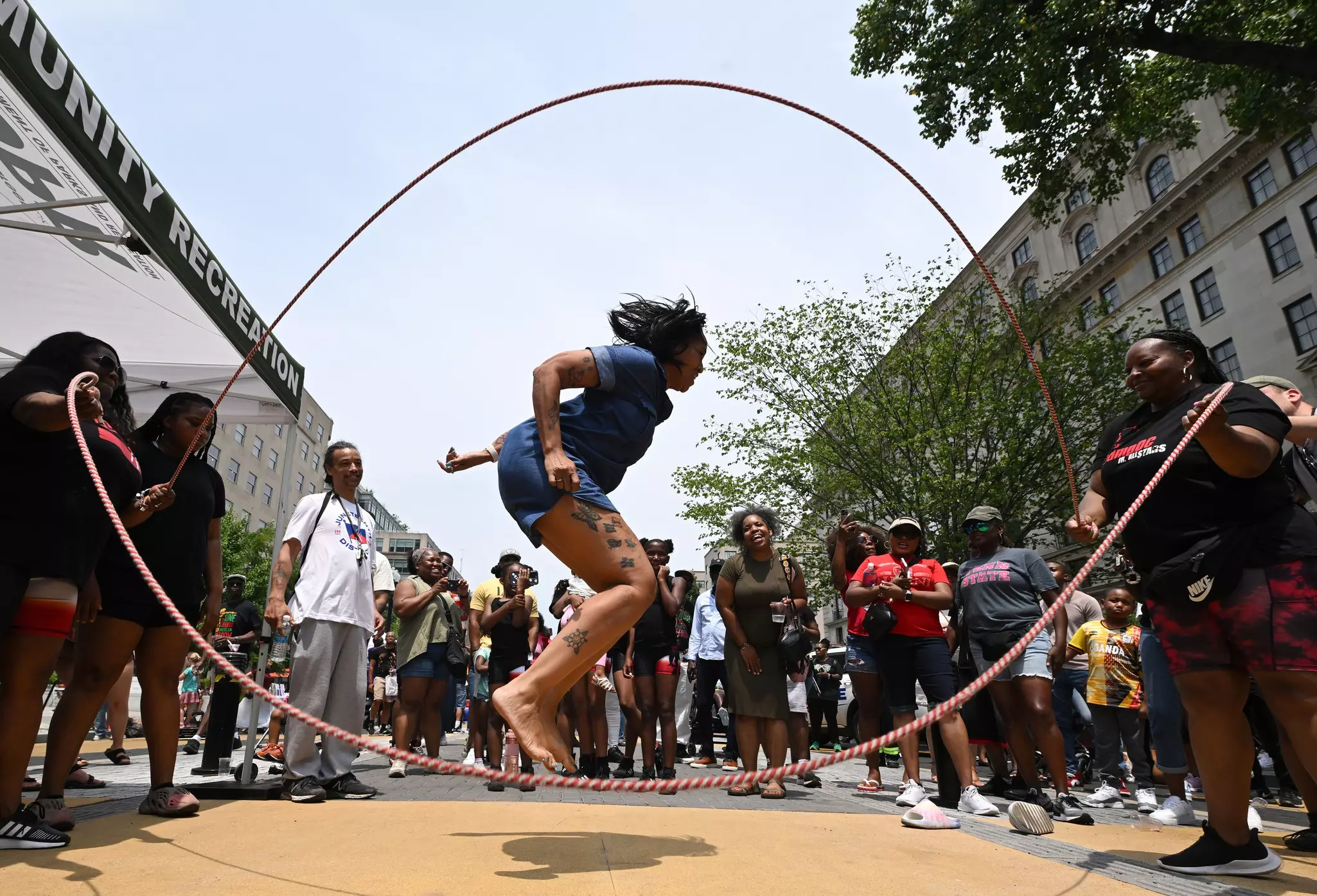 A woman jumps double dutch as a small group gathers around during a Juneteenth event along Black Lives Matter Plaza in Washington, DC