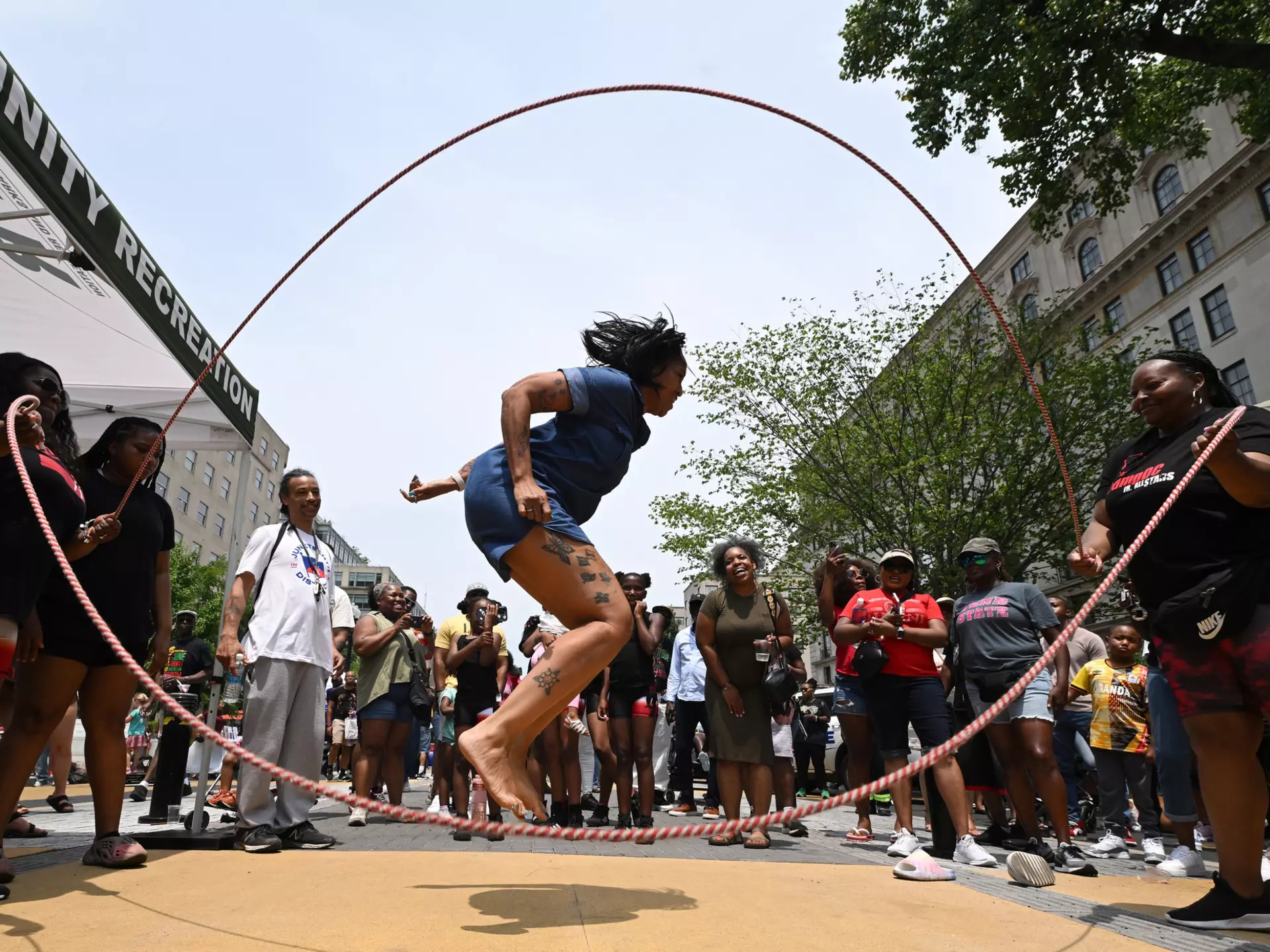 A woman jumps double dutch as a small group gathers around during a Juneteenth event along Black Lives Matter Plaza in Washington, DC