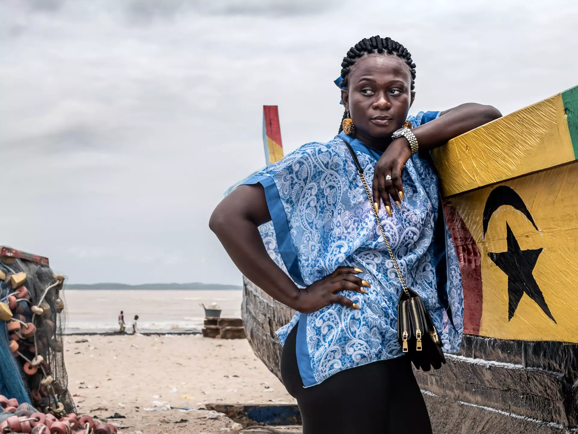A woman stands by a fishing boat on one of the beaches in Ghana
