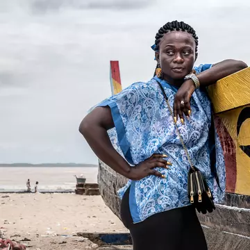 A woman stands by a fishing boat on one of the beaches in Ghana