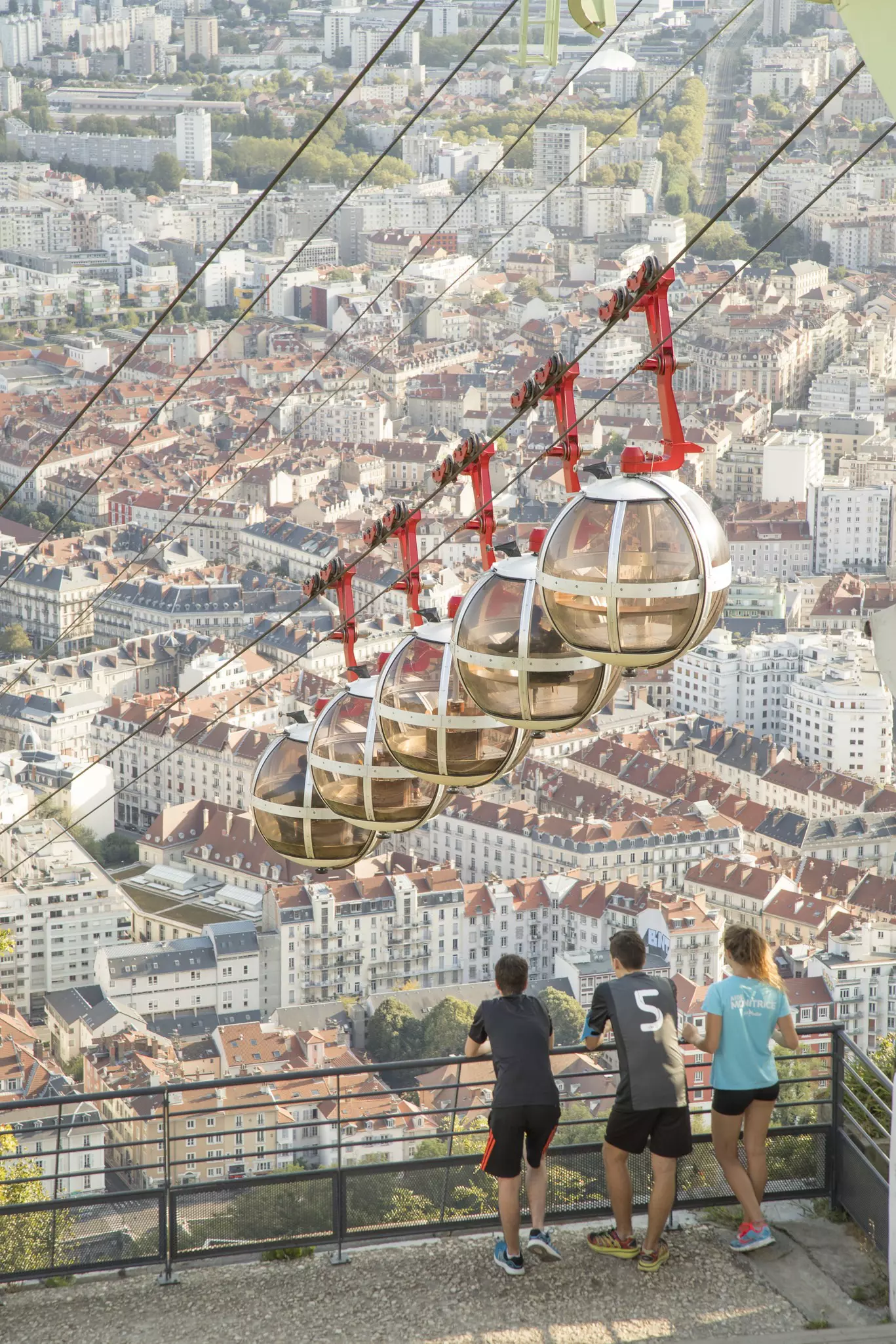 People watch pods from the Grenoble Bastille Cable Car rise above the city of Grenoble.