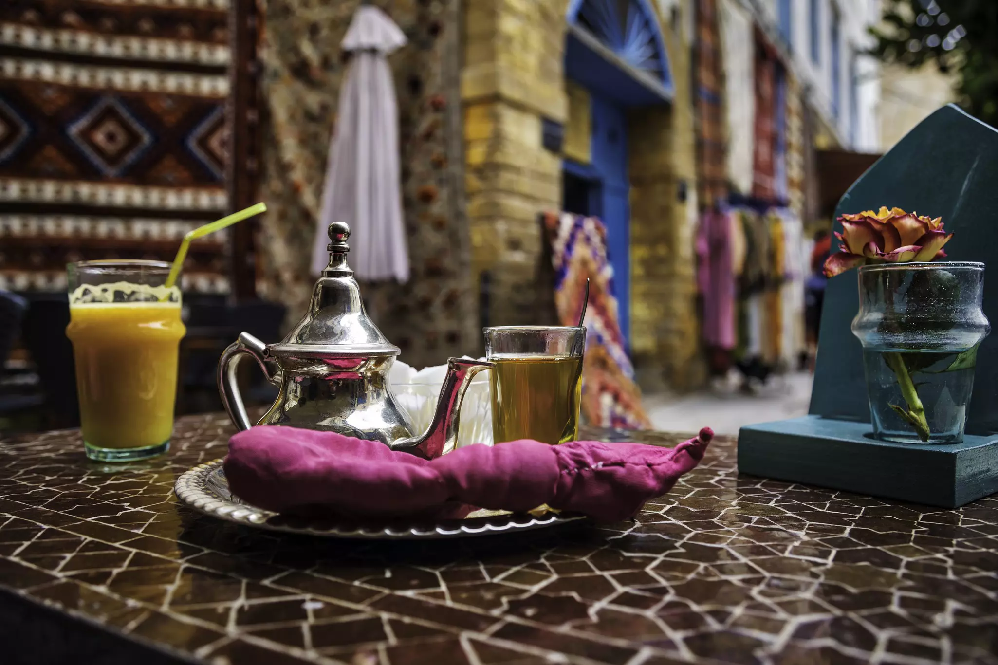 A silver teapot on a tray with a glass of mint tea served in a souq