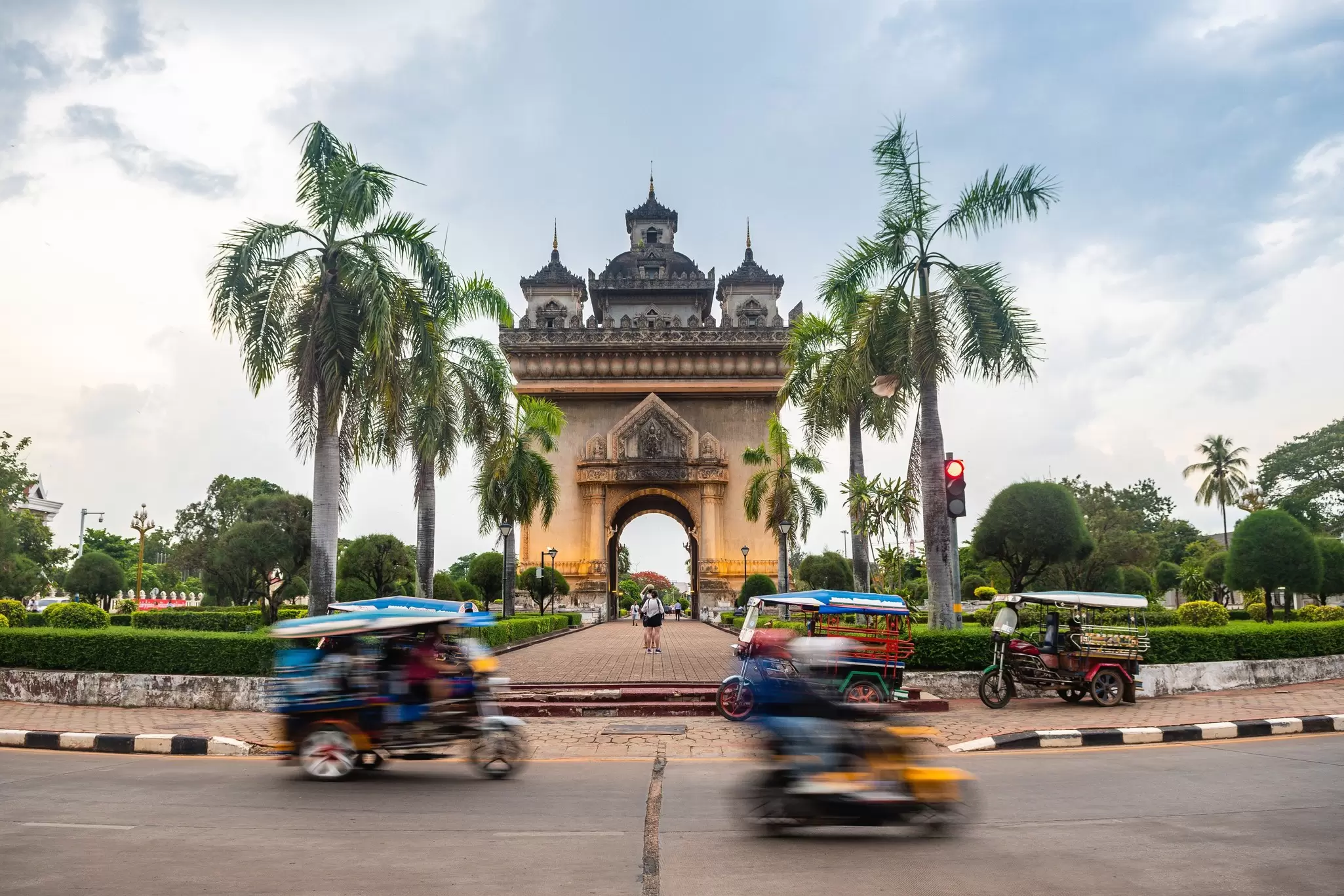 Tuk-tuks pass the Patuxai monument in central Vientiane, Laos. Jon Chica/Shutterstock
