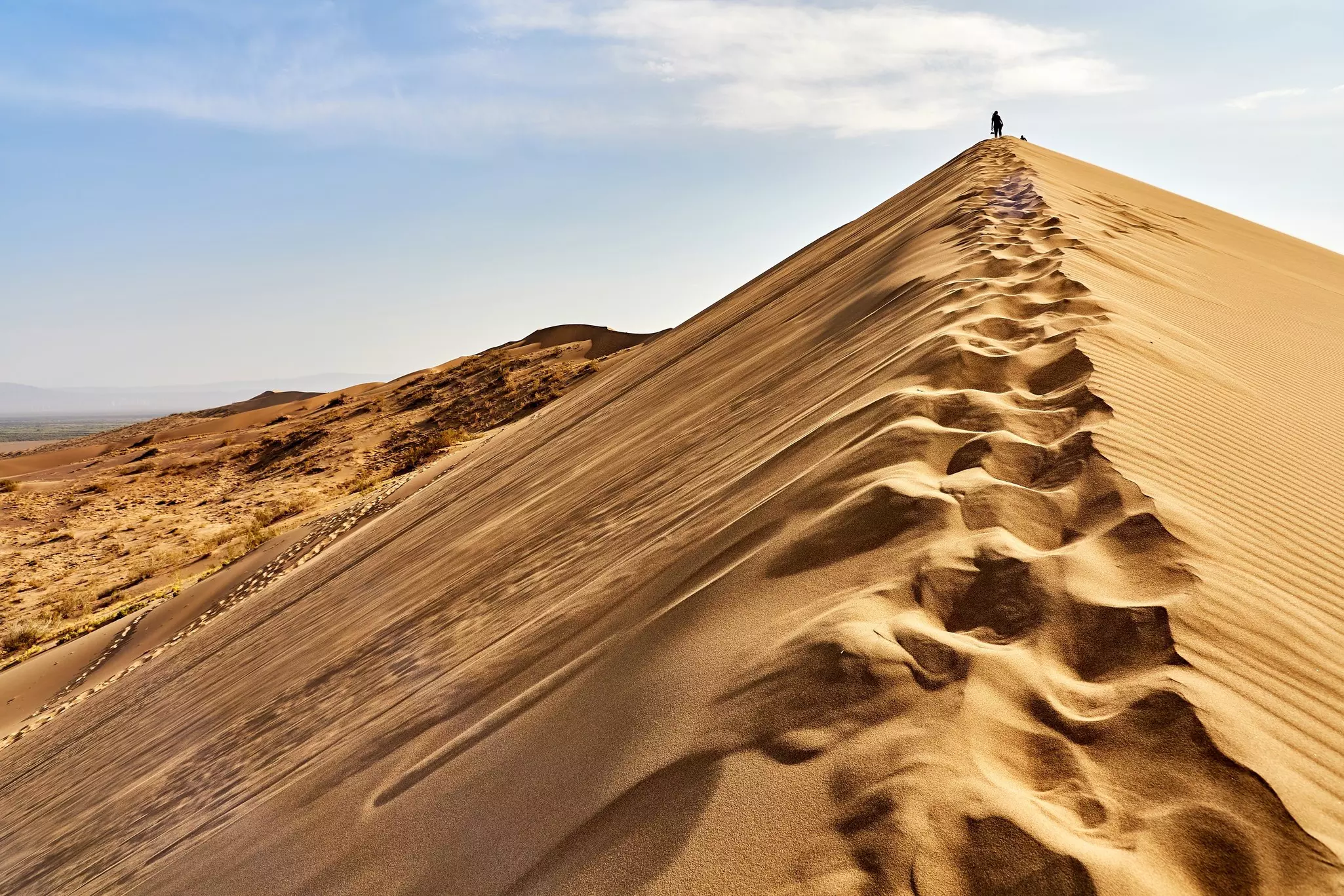 A man standing on the peak of the dunes at Altyn Emel National Park.