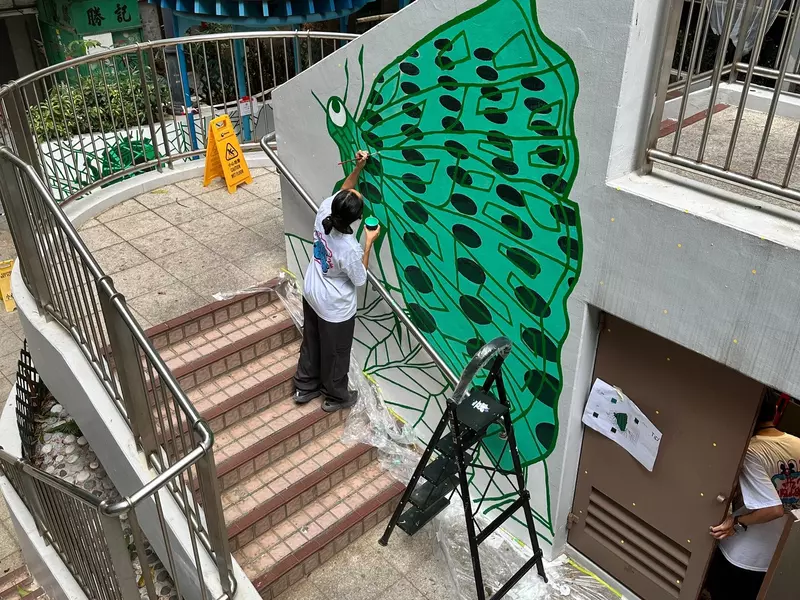 An artist painting a mural on a wall in Hong Kong