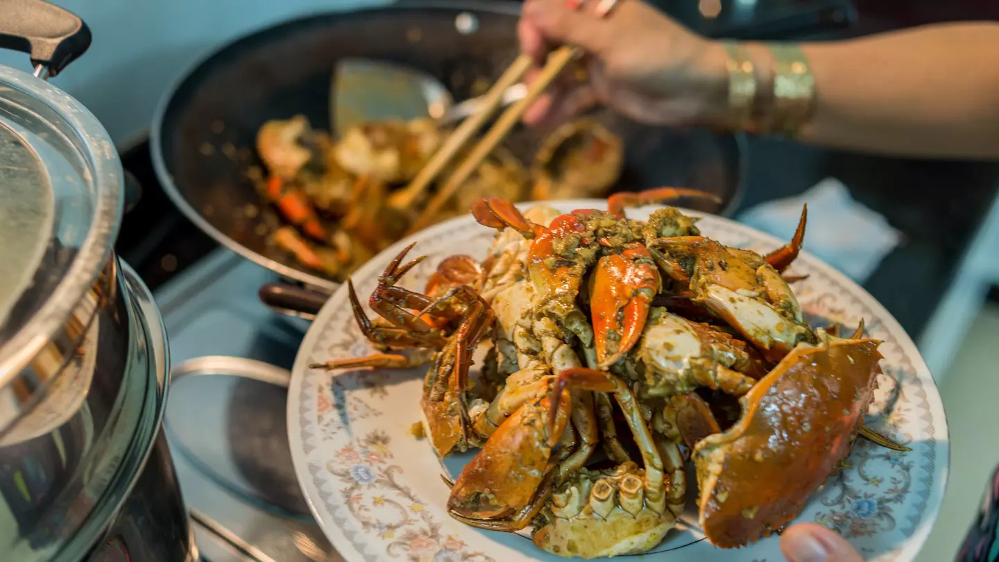 A lady prepares home-cooked chili crab for a family dinner.