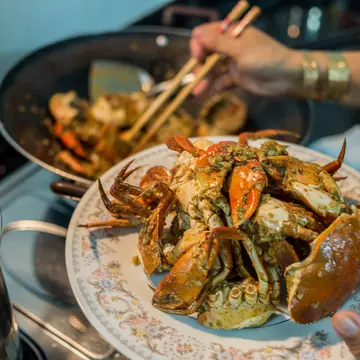 A lady prepares home-cooked chili crab for a family dinner.