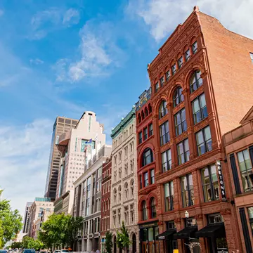 Street view of Louisville, Kentucky, with buildings on both sides and clock on a street post in the foreground.