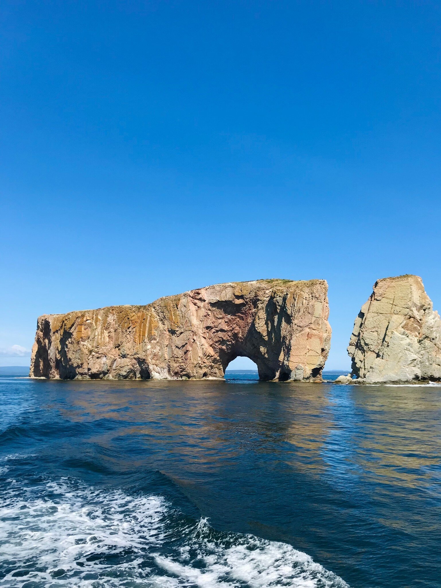 View of the Rocher Percé (Percé Rock) rising from the sea on a sunny day in Canada.