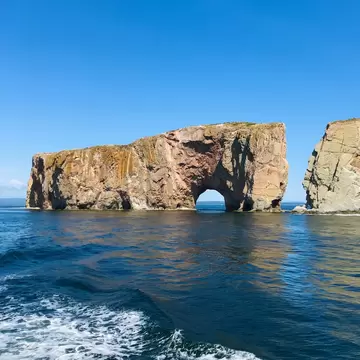 View of the Rocher Percé (Percé Rock) rising from the sea on a sunny day in Canada.