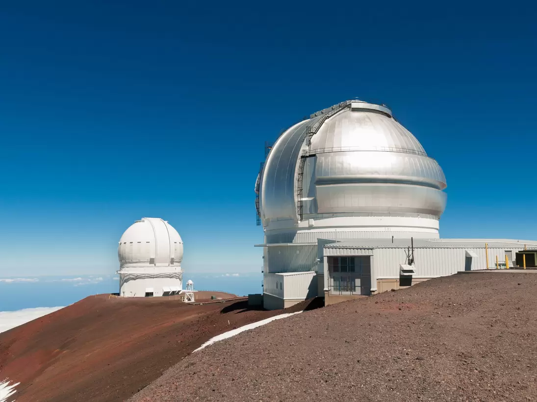 Gemini North Observatory on top of Mauna Kea mountain peak on Big Island of Hawaii, United States with deep blue sky and volcanic landscape.