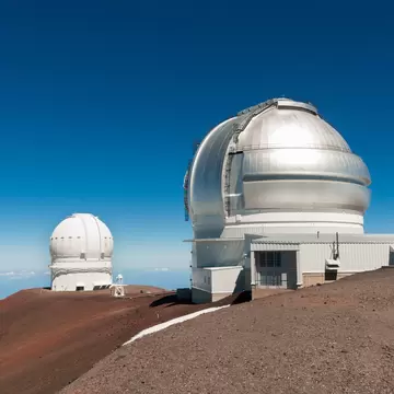 Gemini North Observatory on top of Mauna Kea mountain peak on Big Island of Hawaii, United States with deep blue sky and volcanic landscape.