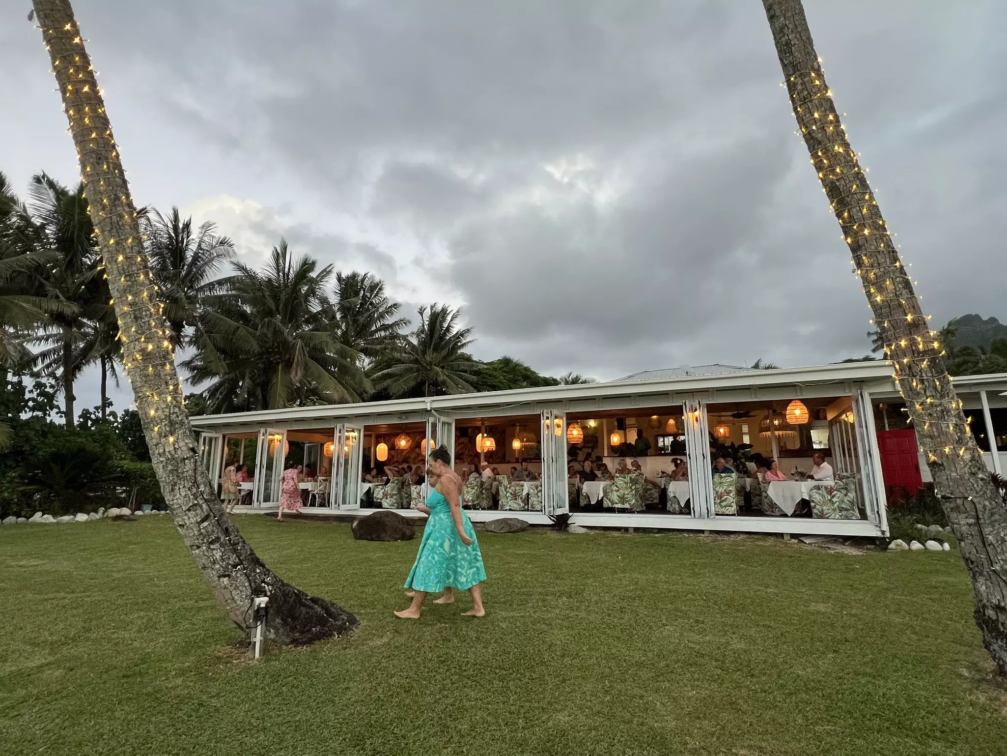 A large garden surrounding a restaurant with open floor-to-ceiling windows