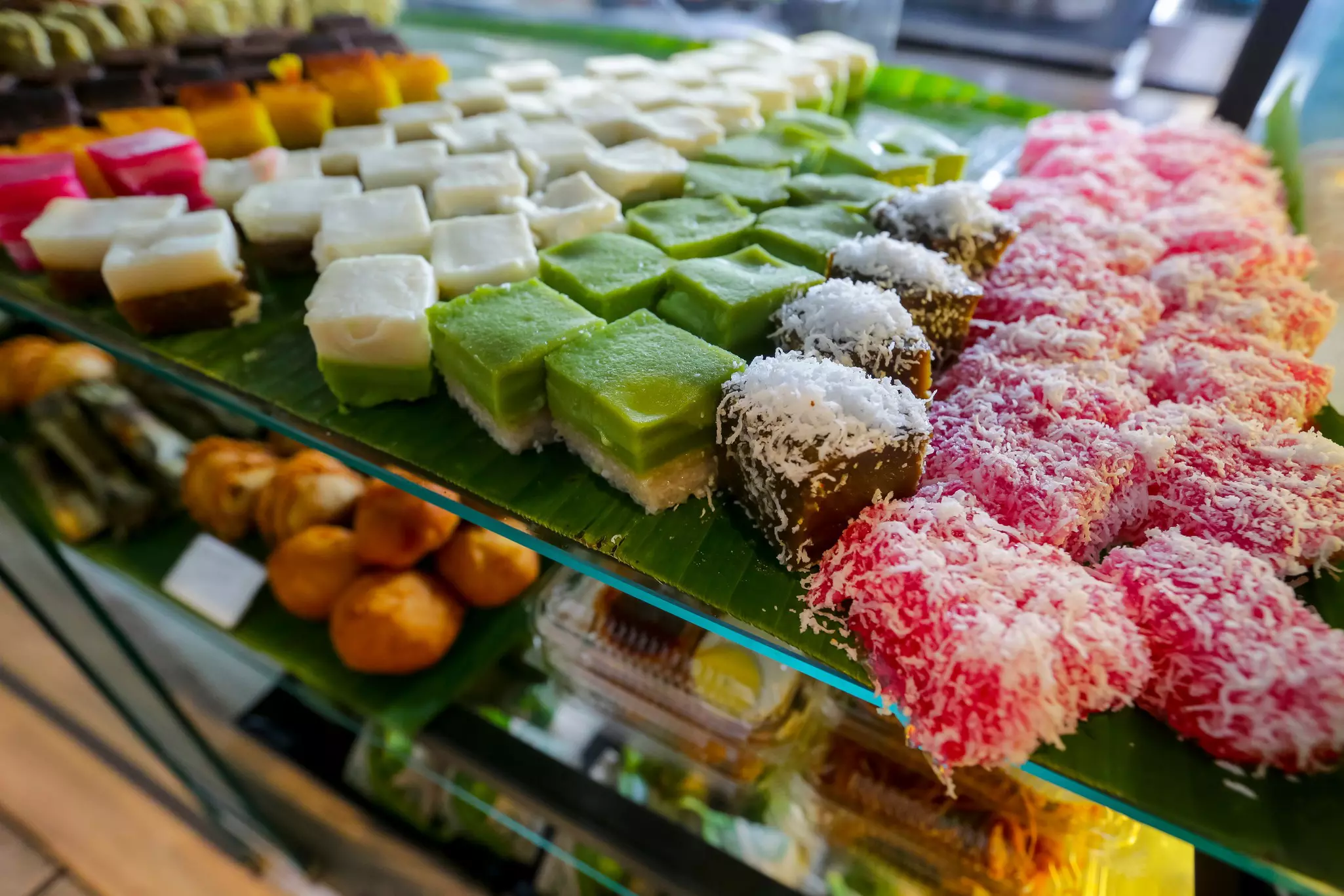 Colorful pastries for sale are displayed on shelves in a bakery.
