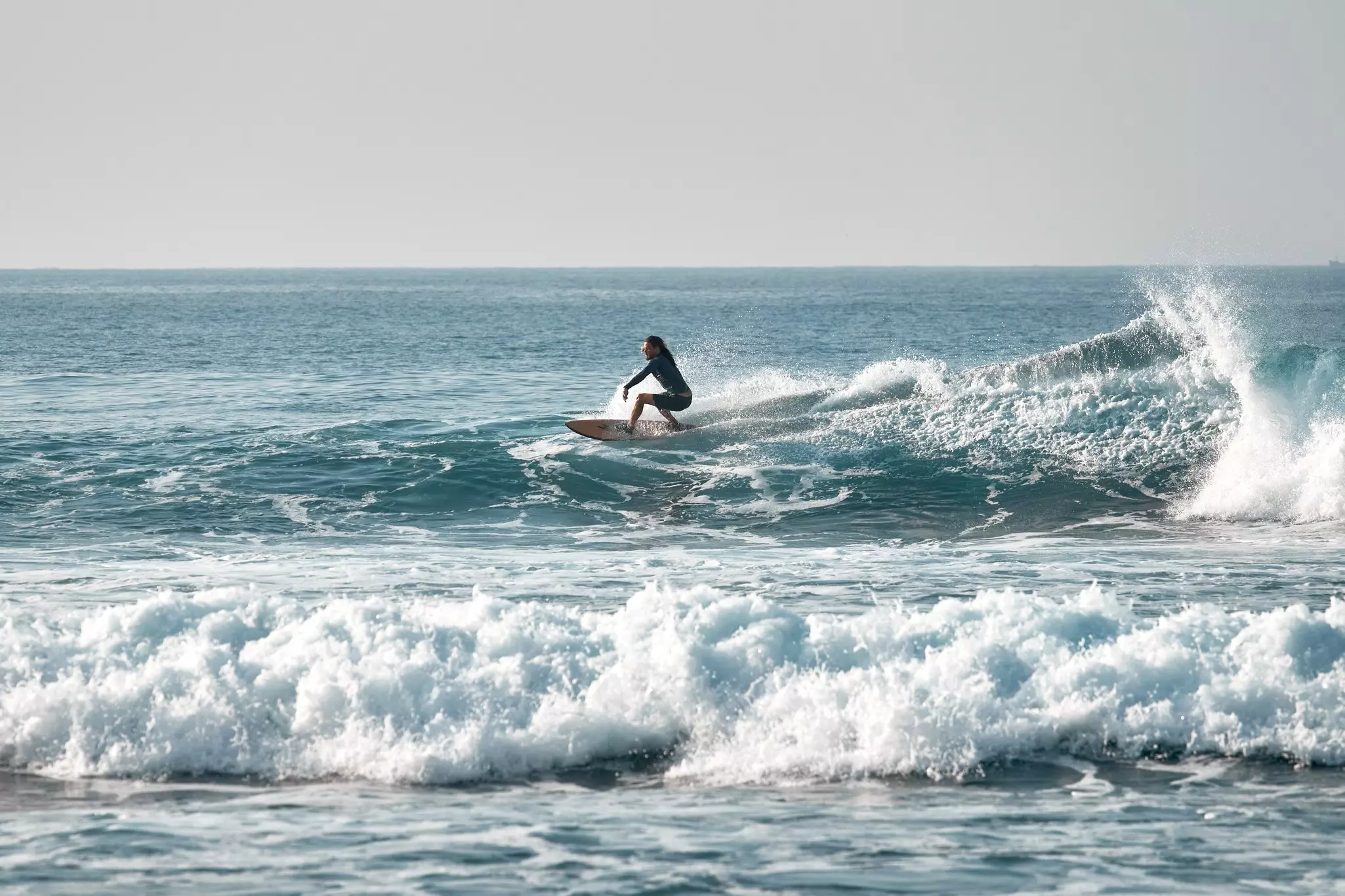 A person rides a wave on a surfboard.