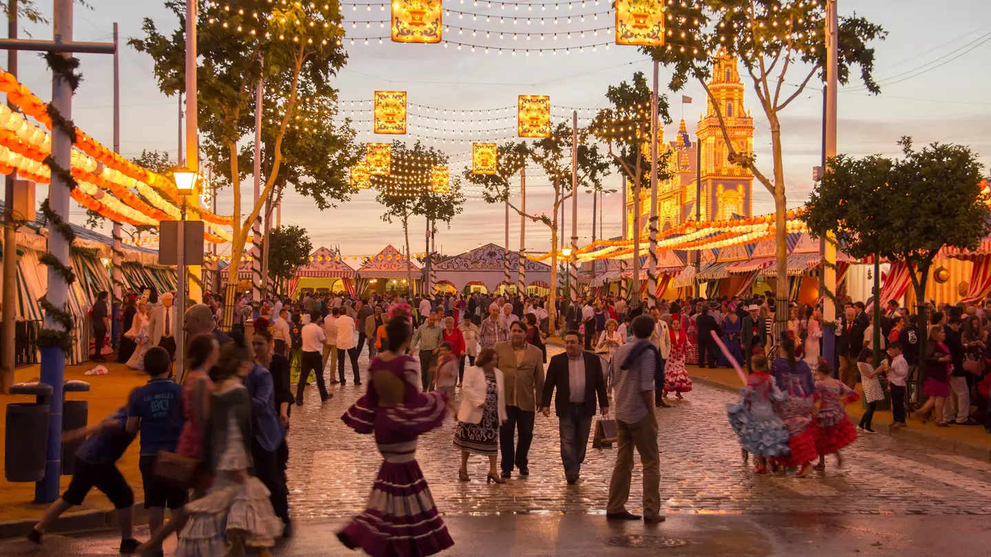 People walking on the sunset street and celebrating at the Seville's April Fair in Seville, Spain.