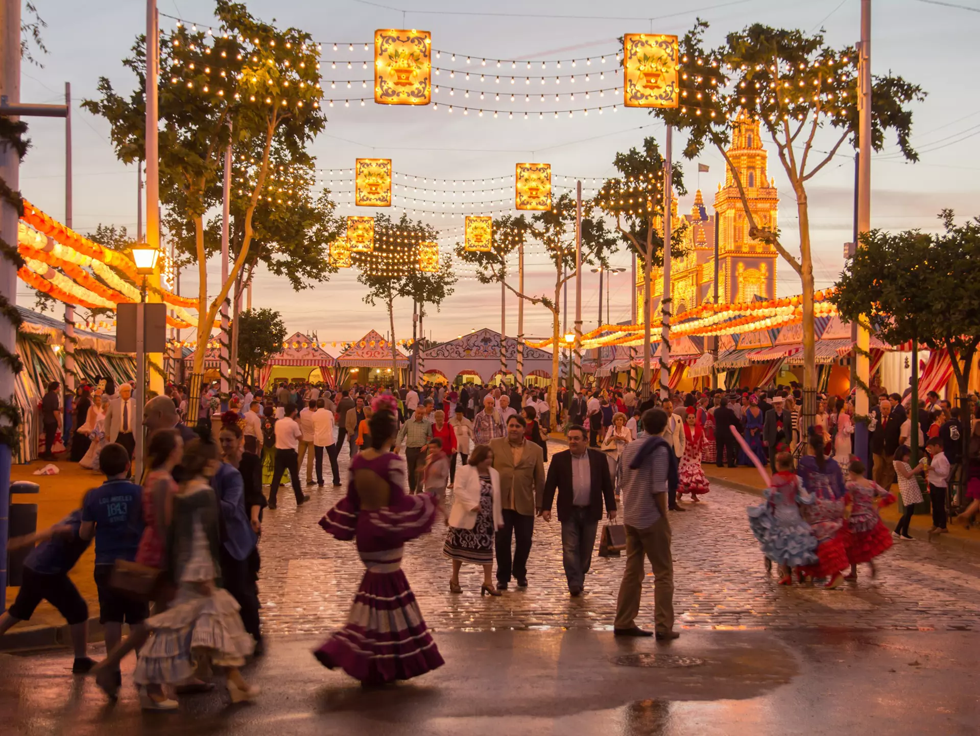 People walking on the sunset street and celebrating at the Seville's April Fair in Seville, Spain.