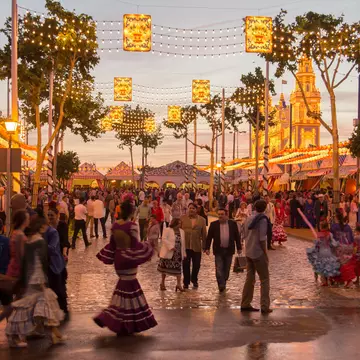 People walking on the sunset street and celebrating at the Seville's April Fair in Seville, Spain.