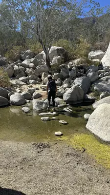 Trail made of boulders with water surrounding and mountain in background. 