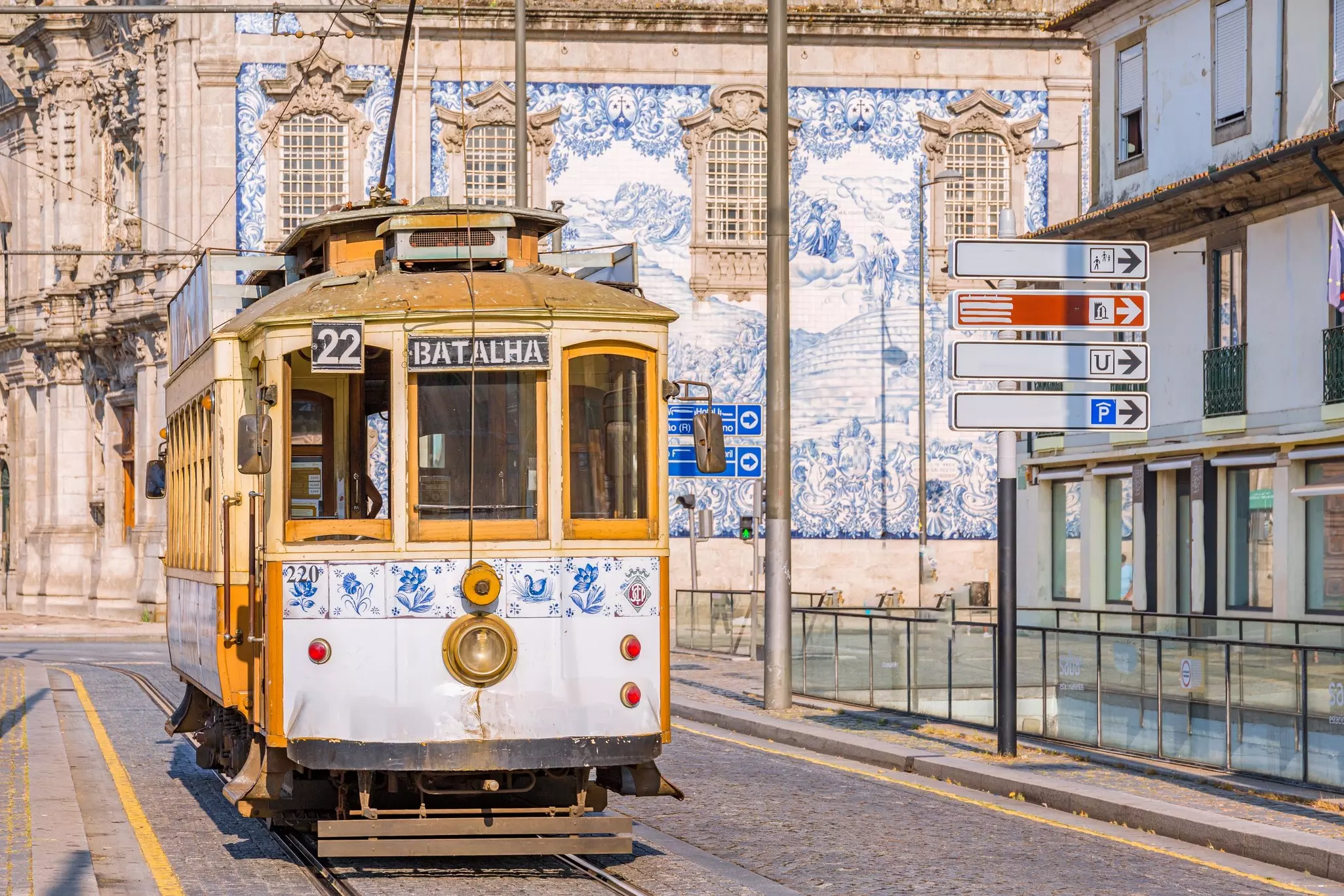 Tram on cobblestone street with tiled buildings in the background.