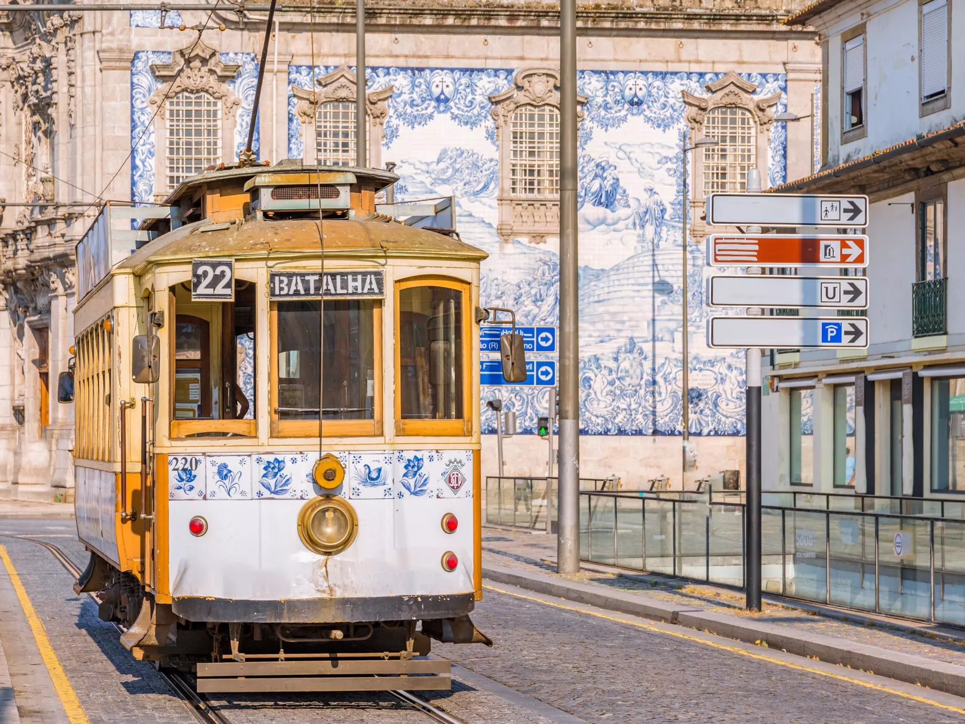 Blue-and-white decorative tiles on a building behind a tram.