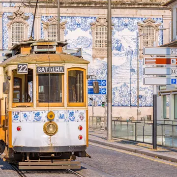 Blue-and-white decorative tiles on a building behind a tram.